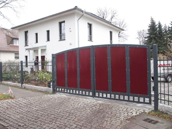 Einfamilienhaus mit rotem Tor und Kopfsteinpflasterweg.