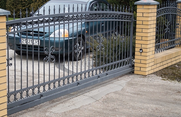 Schmiedeeisernes Tor und Auto auf Einfahrt.