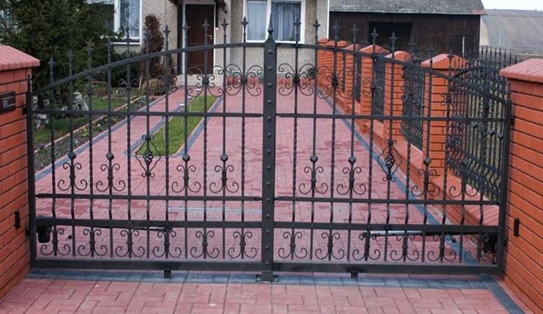 Schmiedeeisernes Gartentor mit Ziegelsteintreppe.