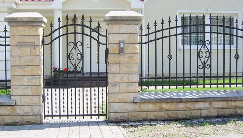 Elegantes schmiedeeisernes Gartentor mit Steinpfosten.