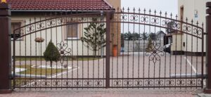 Verziertes Metalltor vor einem Einfamilienhaus.