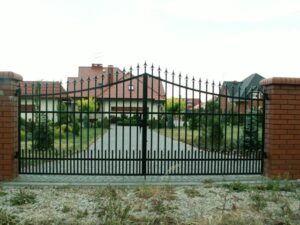 Eisernes Tor vor Einfamilienhaus mit Garten.