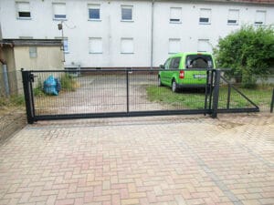 Metalltor vor Wohnblock mit grünem Auto.