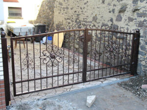 Eisernes Tor mit dekorativen Elementen, Baustelle im Hintergrund.