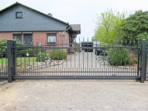 Metalltor vor einem Einfamilienhaus mit Einfahrt.