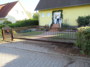 Haus mit Zaun und Person auf Veranda.