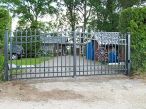 Verschnörkeltes Eisentor vor Einfahrt mit Auto.