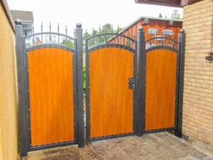 Holztor mit schmiedeeisernen Verzierungen an Zufahrt.