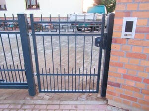 Schmiedeeisernes Tor an einem Ziegelsteinhaus.