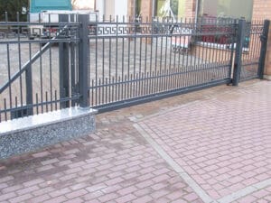 Schmiedeeisernes Tor vor Einfahrt mit Pflastersteinen.