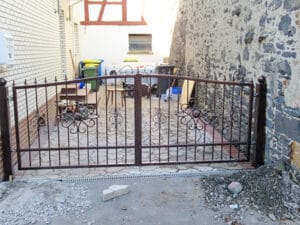 Verziertes Eisentor vor einem Innenhof.