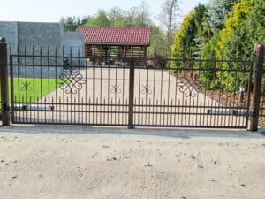 Schmiedeeisernes Gartentor mit Einfahrt und Grünanlage