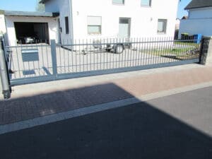 Haus mit Einfahrtstor und gepflasterter Zufahrt.