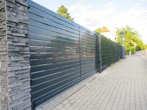 Metallzaun an einem Gehweg mit Steinsäule.