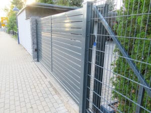 Metalltor und Zaun an Gehweg.