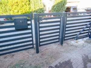 Schwarzes Gartentor und Briefkasten am Zaun.