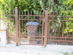 Verzierter Eisentor-Eingang mit Hecke.