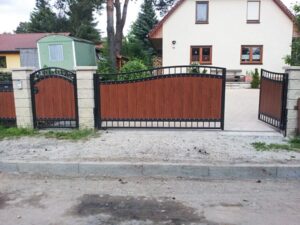 Einfahrtstor vor Wohnhaus mit Gartenzaun.