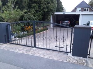 Metallgartentor an einer Einfahrt mit Auto im Hintergrund.