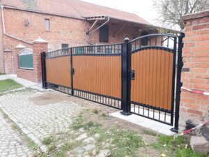 Neues, braunes Metalltor vor Ziegelhaus.
