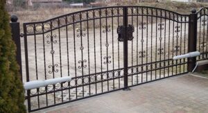 Schmiedeeisernes Tor mit Zierelementen und Auffahrt.