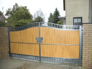 Holztor mit Metallverzierung und Adlertopf.