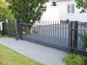 Schwarzes Metalltor und Zaun bei Einfahrt.