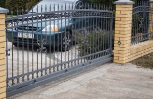 Schmiedeeisernes Tor und Auto auf Einfahrt.