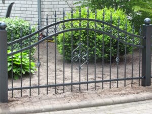 Schmiedeeisernes Gartentor vor Hecken.