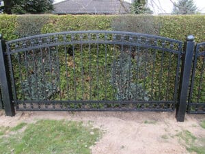 Schmiedeeisernes Gartentor vor Hecke.