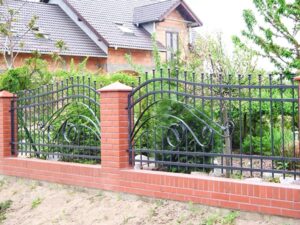 Schmiedeeisernes Gartentor mit Ziegelsteinpfosten.