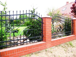 Eisernes Gartentor mit Ziegelsäulen und Grünanlage.