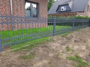 Dekorativer Metallzaun vor einem Wohnhaus.