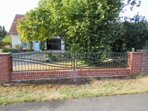 Einfamilienhaus mit Gartenzaun und Bäumen in Deutschland.