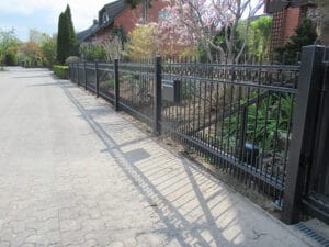 Straße mit Metallzaun und blühenden Bäumen.