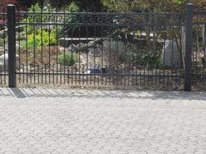 Metallzaun und gepflasterter Weg im Garten.