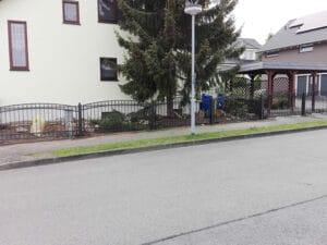 Straßenansicht mit Wohnhäusern und Gartenzaun.