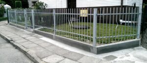 Metallzaun und Gehweg an einem Wohnhaus.
