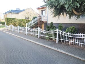 Einfamilienhaus mit weißem Zaun und Vorgarten.
