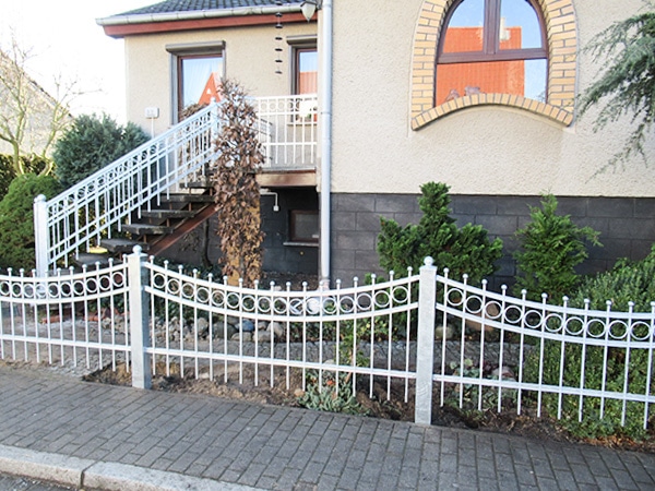 Haus mit Außentreppe und weißem Zaun.