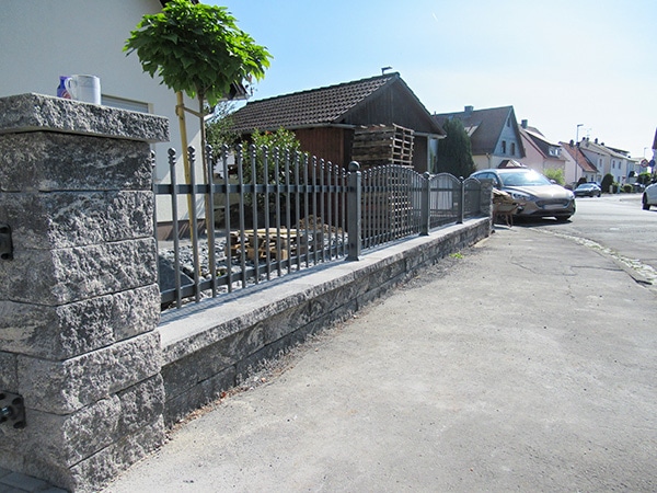 Steinmauer mit Metallzaun an einer Straße in Deutschland