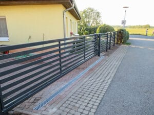 Metallgeländer und Gepflasterter Gehweg am Haus.