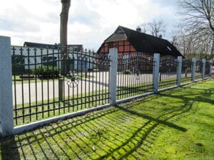 Metalltor und Zaun mit Schatten auf Rasenfläche.