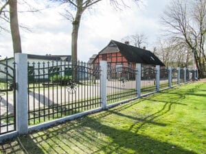 Schmiedeeisernes Tor vor traditionellem Haus mit Garten.