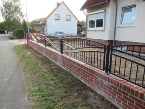 Ziegelmauer mit Metallgeländer an einem Wohnhaus.