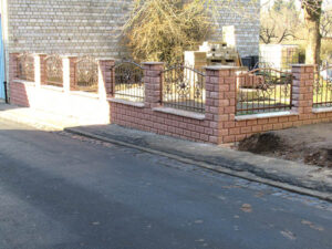 Zaun und Gehweg an sonnigem Tag.