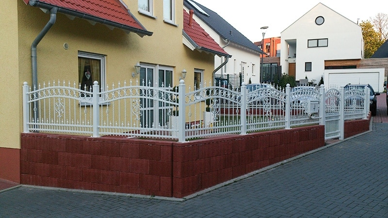 Haus mit weißem Zaun und roter Mauer.