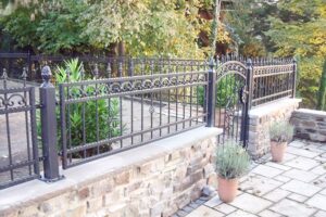 Schmiedeeiserner Zaun an Terrasse mit Pflanzen.