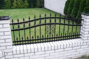 Eisernes Gartentor mit dekorativen Elementen und Grünanlage