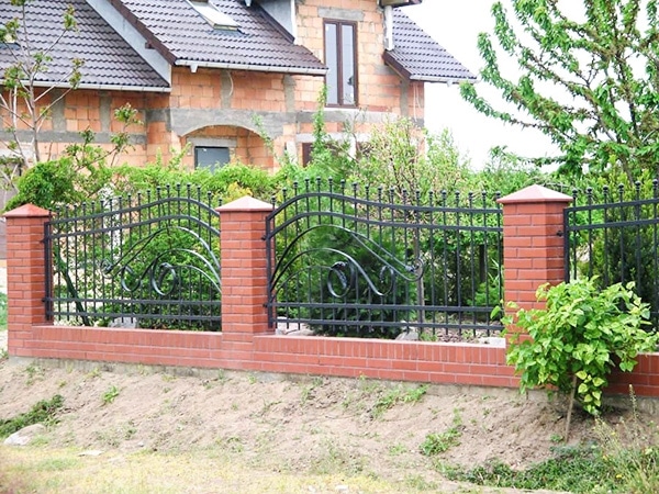 Zaun aus Ziegel und Metall vor einem Haus.